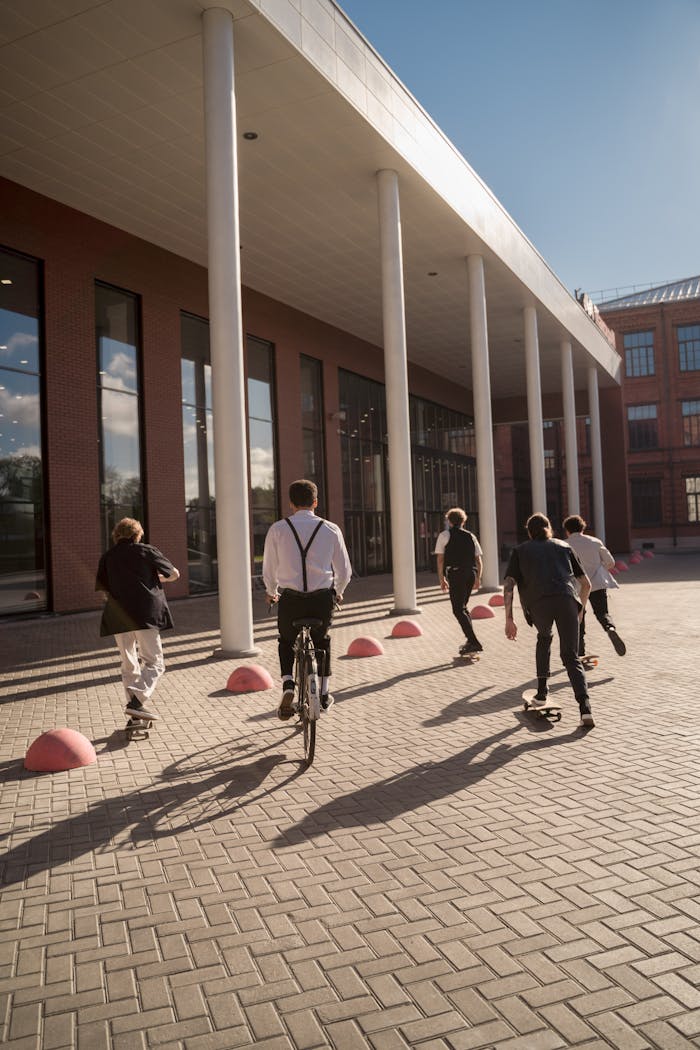 Dynamic scene of skateboarders and a cyclist on a sunny day near a modern building.