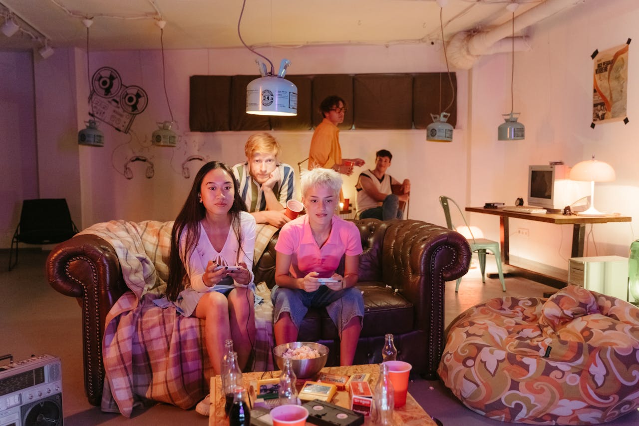 Group of friends enjoying a fun video game night indoors, sitting together on couches.